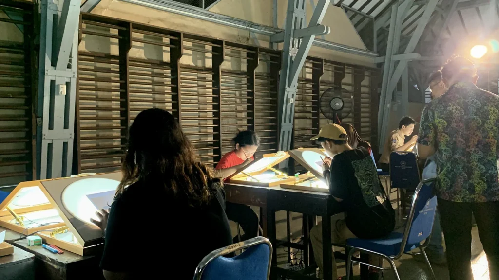 Peserta mewarnai frame rotoscoping di meja workshop Tracing The Heritage oleh Rimbun Project, Kotabaru Heritage Film Festival 2025.