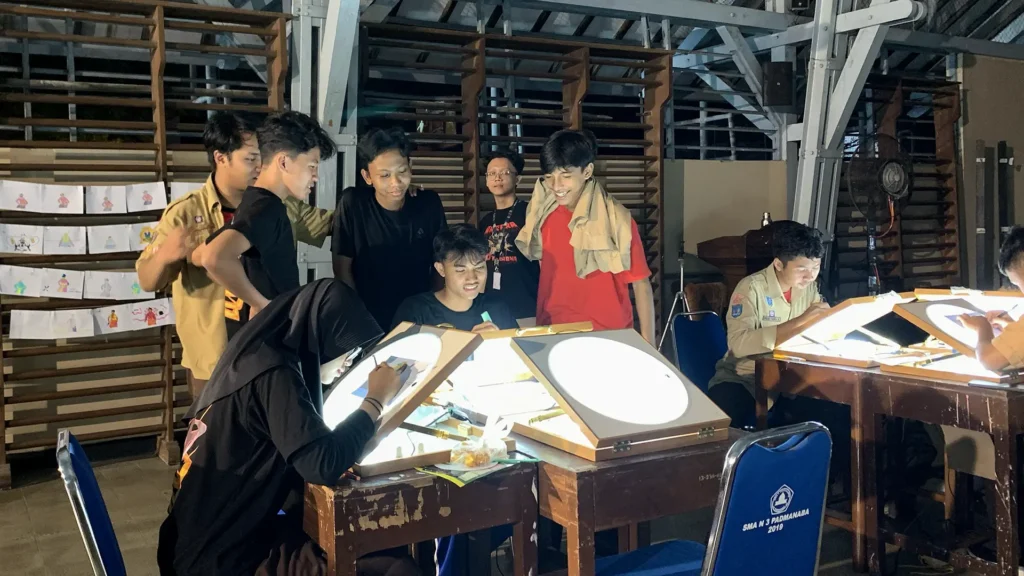 Peserta mewarnai frame rotoscoping di meja workshop Tracing The Heritage oleh Rimbun Project, Kotabaru Heritage Film Festival 2025.