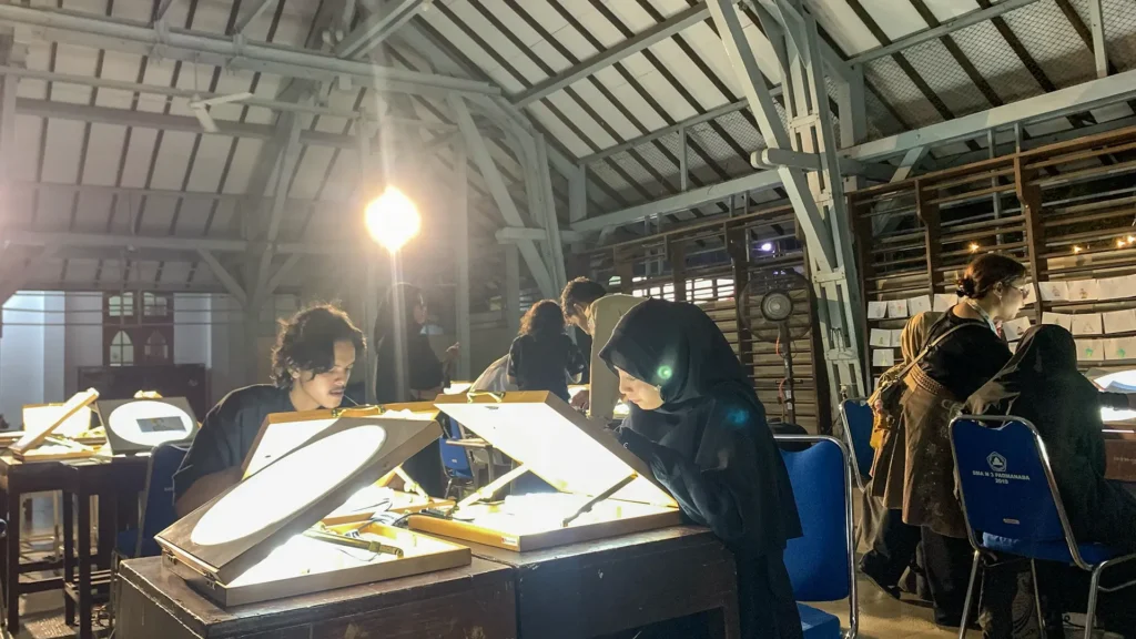 Peserta mewarnai frame rotoscoping di meja workshop Tracing The Heritage oleh Rimbun Project, Kotabaru Heritage Film Festival 2025.