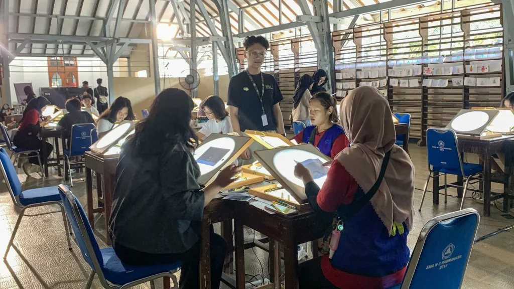 Peserta mewarnai frame rotoscoping di meja workshop Tracing The Heritage oleh Rimbun Project, Kotabaru Heritage Film Festival 2025.