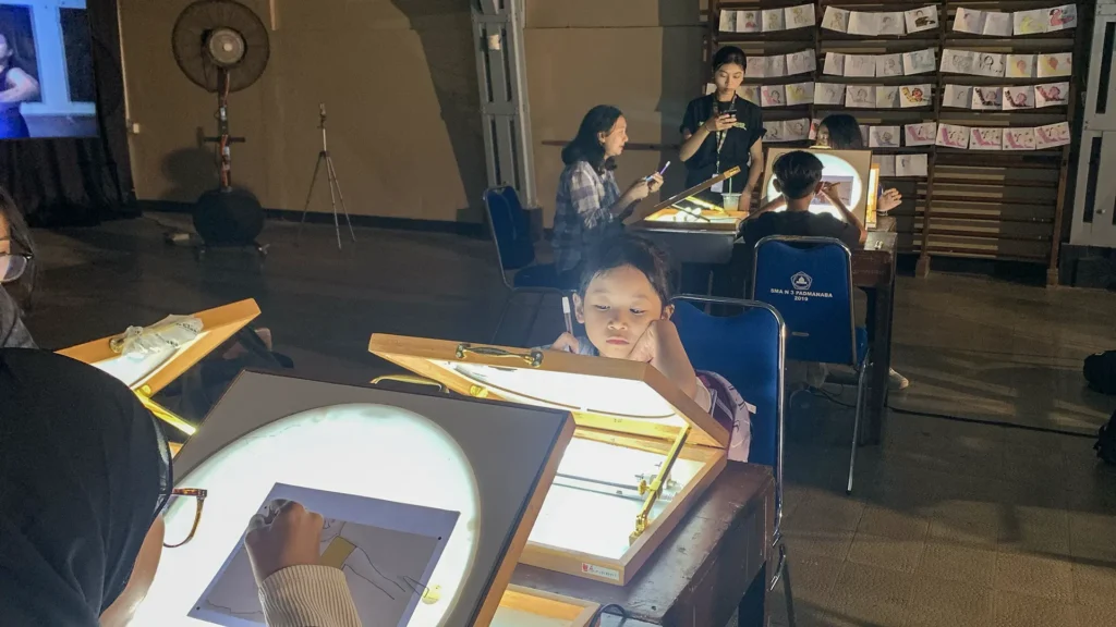 Peserta mewarnai frame rotoscoping di meja workshop Tracing The Heritage oleh Rimbun Project, Kotabaru Heritage Film Festival 2025.