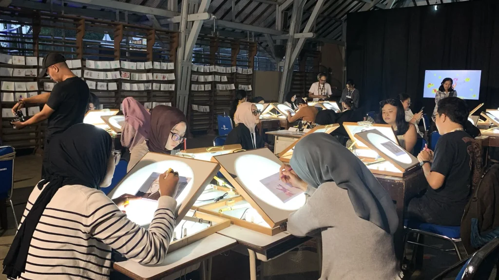 Peserta mewarnai frame rotoscoping di meja workshop Tracing The Heritage oleh Rimbun Project, Kotabaru Heritage Film Festival 2025.