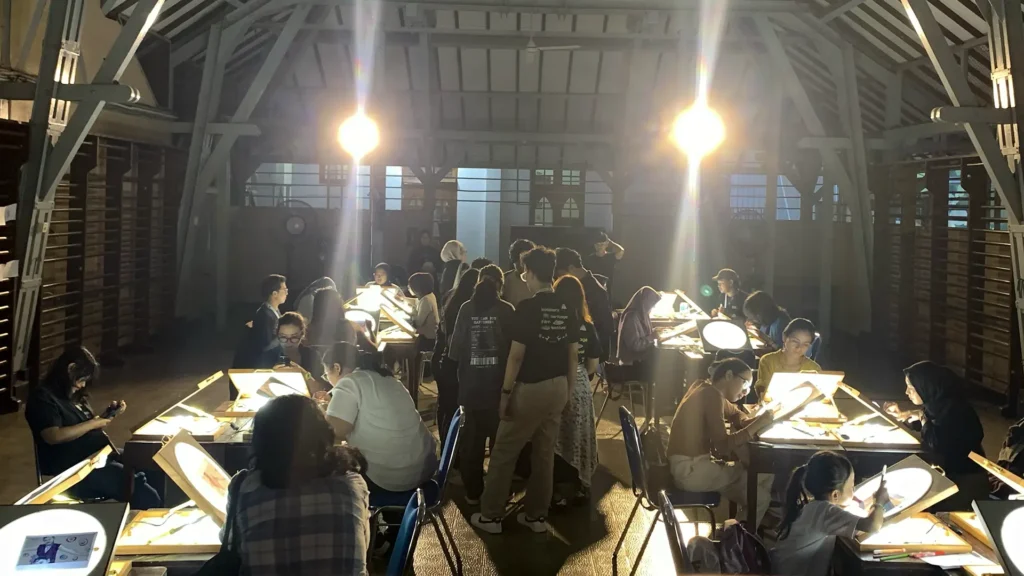 Peserta mewarnai frame rotoscoping di meja workshop Tracing The Heritage oleh Rimbun Project, Kotabaru Heritage Film Festival 2025.